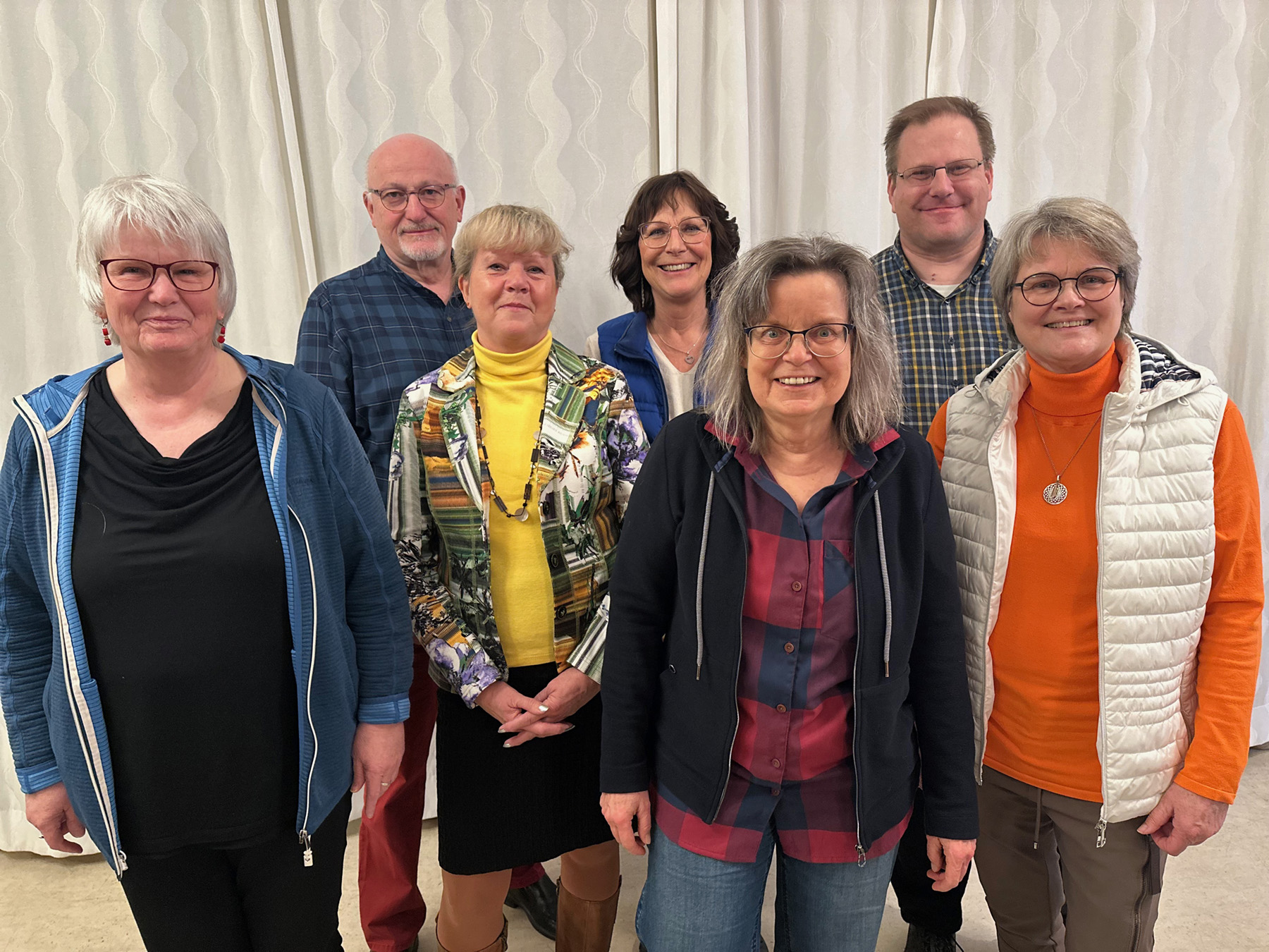 Sieben Personen, die Kandidat*innen für den Teamvorstand, stehen vor einem weißen Vorhang und schauen in die Kamera